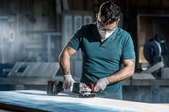 Person schleift Holzplatte mit Schleifmaschine